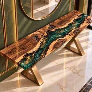 May include: A rectangular console table featuring a live-edge wood slab with a central river-like inlay of translucent teal resin. The table is supported by two angular, metallic gold-finished legs with a geometric, V-shaped base design.