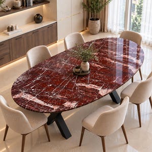 May include: An oval dining table with a polished deep red marble top featuring white veining, supported by a black metal X-shaped base. Six upholstered chairs with light beige fabric and dark wooden legs are arranged around the table.