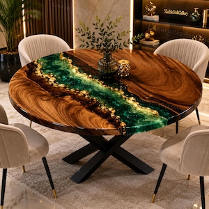 Puede incluir: Una mesa de comedor redonda con un tablero de madera natural y un diseño de río central hecho de resina verde esmeralda translúcida y detalles de pan de oro, sobre una base de metal negro en forma de X, rodeada por cuatro sillas beige.
