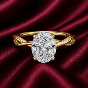 Puede incluir: Un anillo de oro con una gran piedra preciosa transparente de talla ovalada y facetada, sujeta por cuatro garras. La banda está hecha de oro amarillo pulido y presenta un diseño trenzado y cruzado a ambos lados del engaste central.