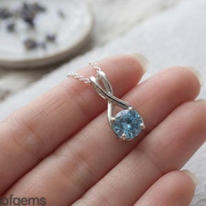 Collar con colgante de moissanita azul cielo y lazo infinito de plata de ley, joyería minimalista.