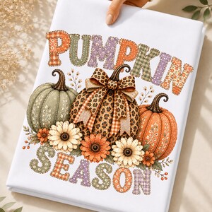 Peut inclure: Un tissu blanc avec une impression graphique portant le texte PUMPKIN SEASON. Le motif comprend une citrouille verte, une citrouille centrale à imprimé léopard avec un nœud et une citrouille orange, agrémentées de fleurs crème et orange.