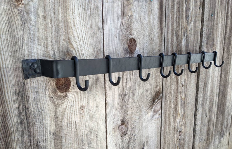 Side view of pot rack on barnwood wall showing empty standard hooks.