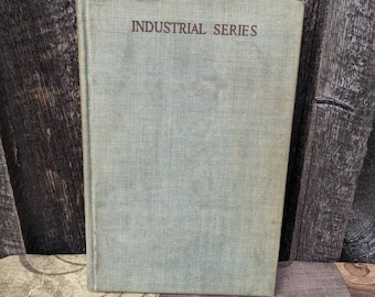 Könnte beinhalten: Ein grünes Vintage-Buch mit dem Titel "INDUSTRIAL SERIES" in brauner Schrift auf dem Einband.
