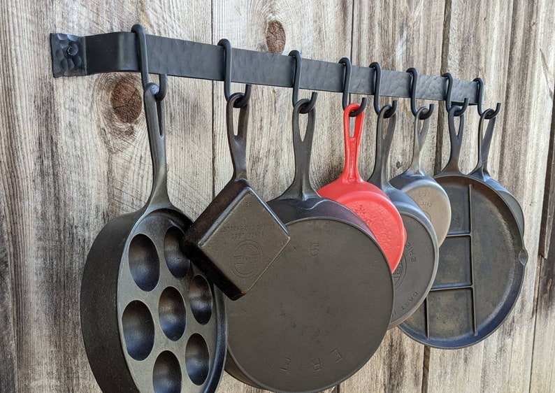 36" long pot rack made of a single piece of steel, shown with 8 movable hooks displaying a range of vintage cast iron pans