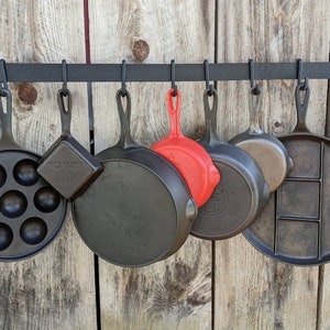 Pot rack shown front view, displaying cast iron pans of varying sizes.