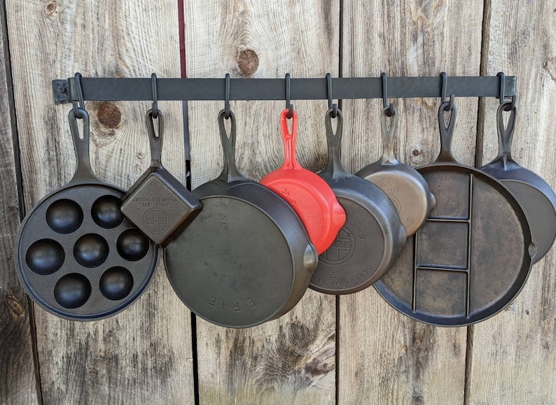 Pot rack shown front view, displaying cast iron pans of varying sizes.