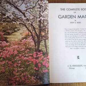 May include: A book titled "The Complete Book of Garden Magic" by Roy E. Biles. The cover features a photograph of a lush garden path lined with pink flowers and trees.