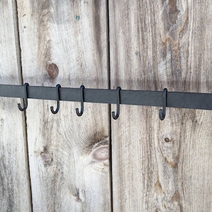 Rack is shown complete with 8 standard, movable hooks, mounted on a barnwood wall.