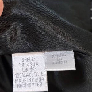 Pode incluir: Uma etiqueta branca com texto preto que diz "SHELL: 100% SILK LINING: 100% ACETATE MADE IN CHINA RN#107768" e uma etiqueta branca menor com texto preto que diz "MADE IN CHINA".