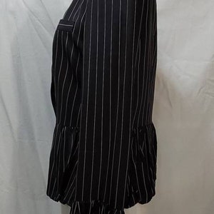 Pode incluir: Um blazer preto e branco listrado com uma bainha franjada. O blazer tem uma silhueta ajustada e um decote sem colarinho.