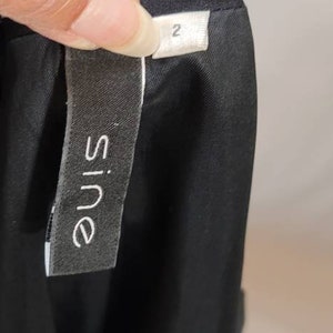 Pode incluir: Vestido listrado preto e branco com uma etiqueta preta que diz "Sine" e uma etiqueta branca que diz "2".