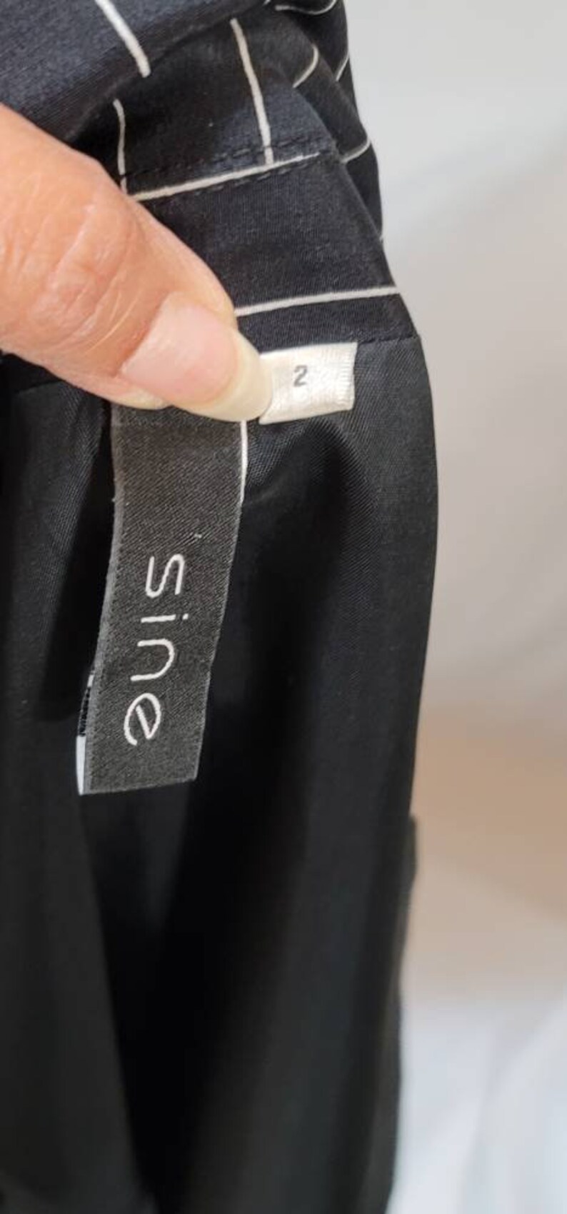 Pode incluir: Vestido listrado preto e branco com uma etiqueta preta que diz "Sine" e uma etiqueta branca que diz "2".