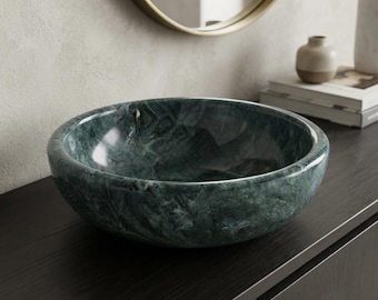 May include: A round vessel sink crafted from dark green marble with natural veining patterns throughout the stone surface. The basin features a smooth, polished finish and a deep, circular bowl shape designed for countertop installation.