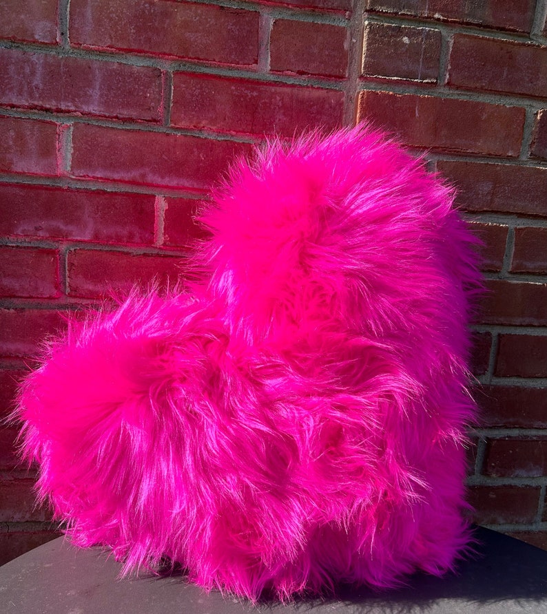May include: A bright pink heart-shaped pillow made of fluffy faux fur.