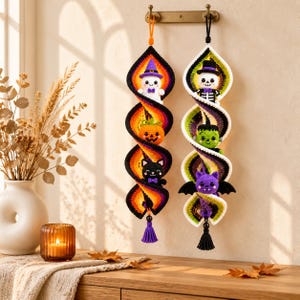 May include: Two vertical crochet spiral decorations hanging from a wall hook. The left spiral features a ghost, pumpkin, and black cat in orange, purple, and black. The right spiral features a skeleton, Frankenstein monster, and bat in green, white, and black.