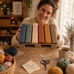 May include: A rectangular crochet organizer featuring six vertical slots in blue, sage green, cream, terracotta, mustard yellow, and brown. The structure is made of textured, ribbed crochet stitches, providing a sturdy base for holding items.