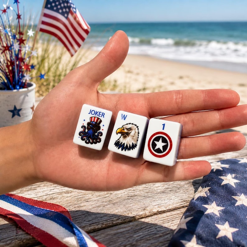 May include: Three white rectangular mahjong tiles featuring patriotic designs. The first tile displays a blue octopus wearing a red, white, and blue top hat with the text JOKER. The second tile shows a bald eagle with the letter W. The third tile has a number 1.