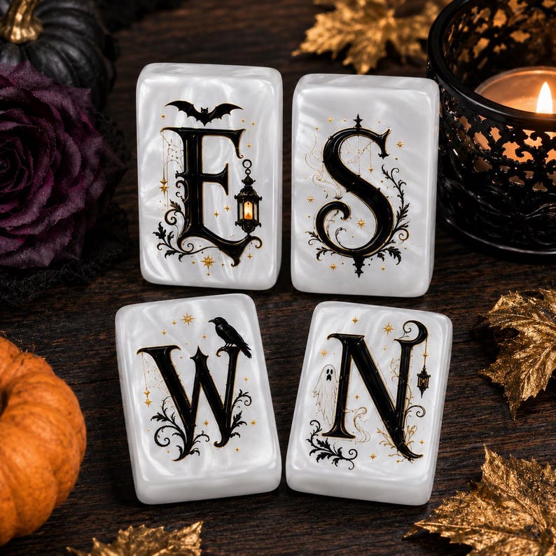 May include: Four rectangular white tiles with a pearlescent finish, each featuring a large black letter forming the word E S W N. The letters are decorated with gold stars, black filigree, a bat, a lantern, a crow, and a ghost illustration.