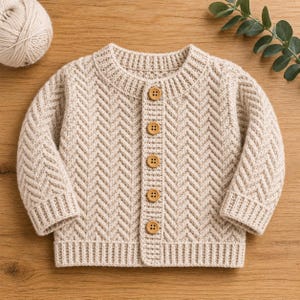 May include: A beige long-sleeve knit cardigan featuring a textured herringbone pattern, a ribbed crew neckline, ribbed cuffs, and a ribbed hem. The front placket is secured with five round, light brown wooden buttons arranged in a vertical line.