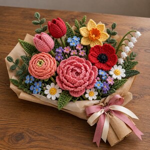 May include: A crochet flower bouquet featuring a large pink peony, a red poppy, a yellow daffodil, pink and red tulips, white daisies, and small blue and purple forget-me-nots. The arrangement includes green crocheted leaves and is wrapped in brown paper with a pink ribbon.