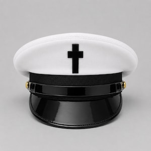 Op de afbeelding: Een witte militaire pet met een opvallend zwart kruisembleem in het midden van de voorzijde. De hoed is voorzien van een zwarte band, een glanzende zwarte lakvizier en twee kleine goudkleurige knopen die de kinband op zijn plaats houden.