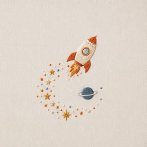 May include: An embroidery design on light fabric featuring a cream-colored rocket ship with orange fins and a blue porthole, accompanied by a blue planet with a ring and a trail of small orange and yellow stars and dots in a curved pattern.
