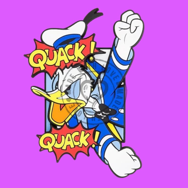 May include: A colorful enamel pin featuring a cartoon duck character in a blue sailor outfit with a white hat. The character is depicted in an action pose with fists raised, surrounded by two red comic-style speech bubbles containing the text QUACK!