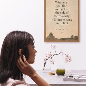 May include: A framed wall art print featuring a beige background with the quote: Whenever you find yourself on the side of the majority, it is time to pause and reflect. Below the text is a silhouette of a city skyline with a large dome.