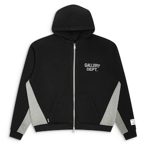 May include: A black zip-up hoodie featuring a hood, long sleeves, and a front kangaroo pocket. The text GALLERY DEPT. is printed in white on the upper right chest. The garment includes grey side panels and a white rectangular label on the left cuff.