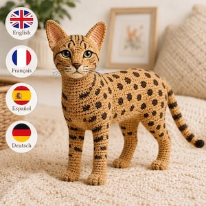 May include: A tan and brown crocheted cat figurine with dark brown spots and stripes, pointed ears, green eyes, and a stitched nose. The cat is standing in a profile position, showcasing detailed yarn texture and a long, slender tail.