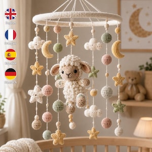 Op de afbeelding: Een babykamer mobiel met een centraal gehaakt crèmekleurig lammetje, omringd door hangende elementen waaronder gele sterren, maansikkels, witte wolken en bollen in gedempte tinten saliegroen, oudroze en beige aan witte koordjes.