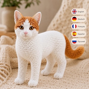 May include: A handcrafted crochet cat figurine featuring a white body with orange patches on the head and a matching orange tail. The cat has amber-colored eyes, a pink nose, and detailed stitching throughout its form, standing in a lifelike pose.