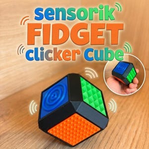 Könnte beinhalten: Ein schwarzer Fidget-Würfel mit farbigen taktilen Seiten, darunter eine blaue Seite mit konzentrischen Kreisen, eine grüne Seite mit einem Gitter aus kleinen Pyramiden und eine orangefarbene Seite mit Noppen. Der Text lautet sensorik FIDGET clicker Cube.