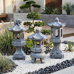 May include: Three gray stone garden lanterns with intricate architectural details. The left lantern features a dragon figure on the roof, the center has a rounded base with swirl carvings, and the right lantern displays cloud motifs on the base.