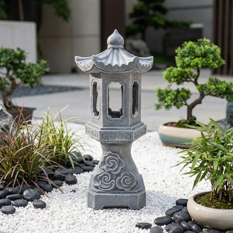 May include: A gray stone pagoda lantern featuring a hexagonal roof, open window panels, and a base decorated with carved cloud motifs. The structure has a weathered texture and stands upright with a tiered design, showcasing intricate geometric patterns.