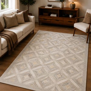 May include: A rectangular area rug featuring a geometric pattern of interlocking squares and diamonds in shades of beige, cream, and light grey. The rug has a low-pile texture and a finished border, covering a portion of the wooden floor.