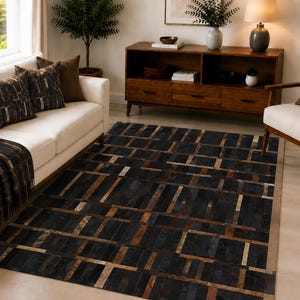 May include: A rectangular area rug featuring a geometric grid pattern composed of stitched leather panels in shades of black, dark brown, and metallic gold. The rug displays a repeating block design with varying rectangular shapes and textures.