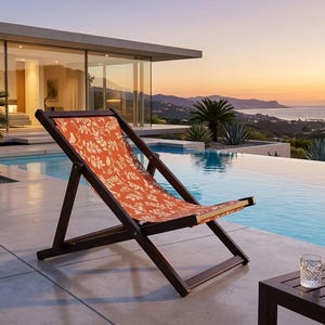 May include: A folding lounge chair with a dark brown wooden frame and a fabric seat featuring a white botanical leaf pattern on an orange background. The chair has a slanted backrest and a horizontal support bar at the base for stability.