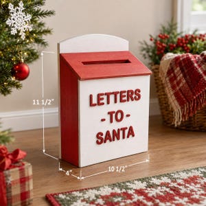 May include: A white and red wooden post box featuring a top slot and the text LETTERS TO SANTA in red raised lettering. The box measures 29.21 cm in height, 26.67 cm in width, and 10.16 cm in depth as indicated by the visible dimension lines.