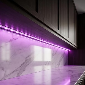 May include: A flexible LED light strip installed under dark wooden kitchen cabinets, emitting a vibrant purple glow onto a white marble countertop and backsplash with grey veining. The strip features visible individual light diodes.