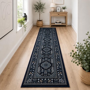 May include: A long, rectangular runner rug featuring a dark navy blue base with intricate, symmetrical geometric and floral patterns in shades of light blue, cream, and grey. The rug has a defined border and a low-pile, flat-woven texture.