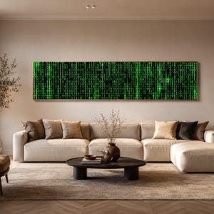 May include: A long, rectangular wall art piece featuring a digital matrix pattern of glowing green binary code consisting of zeros and ones against a black background, displayed in a thin wooden frame above a beige sectional sofa.