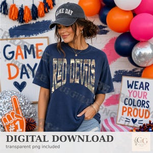 Puede incluir: Una camiseta de manga corta azul oscuro con el texto RED DEVILS en un patrón de camuflaje en el pecho, combinada con una gorra de béisbol azul oscuro a juego con el texto GAME DAY bordado en blanco en el panel frontal.