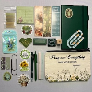 May include: A collection of stationery items including a dark green notebook with a paperclip sticker, a canvas pouch with the text Pray About Everything Worry About Nothing Philippians 4:6, various stickers, bookmarks, pens, and adhesive tabs.