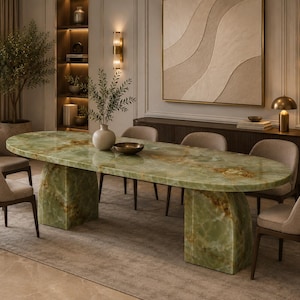 Op de afbeelding: Een ovale eettafel met een gepolijst groen onyx stenen blad en twee bijpassende zware stenen voetstukken, omringd door zes gestoffeerde stoelen met donkerhouten poten, wat een samenhangende meubelset vormt voor een eetkamer.