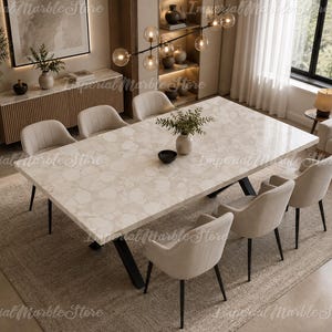 May include: A rectangular dining table featuring a polished beige marble top with a subtle circular pattern and a black metal base. The table is surrounded by six upholstered cream-colored chairs with black legs, arranged in a formal dining setting.
