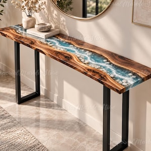 Puede incluir: Una mesa consola larga con un tablero de madera natural de borde vivo y un diseño de río central hecho de resina azul y piedras de río blancas. La mesa está sostenida por dos patas de metal negro en forma de U y tiene un acabado pulido.