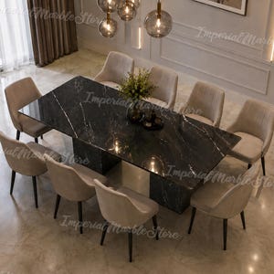 May include: A rectangular dining table with a polished black marble top featuring white veining, supported by a matching black marble pedestal base. Eight upholstered chairs in a light beige fabric with dark legs are arranged around the table.