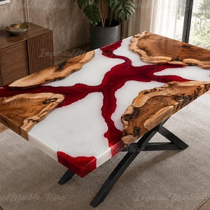 May include: A rectangular dining table featuring a live edge wood slab surface integrated with a white and deep red resin river design. The table is supported by a black metal X-shaped base, showcasing natural wood grain and organic edges.